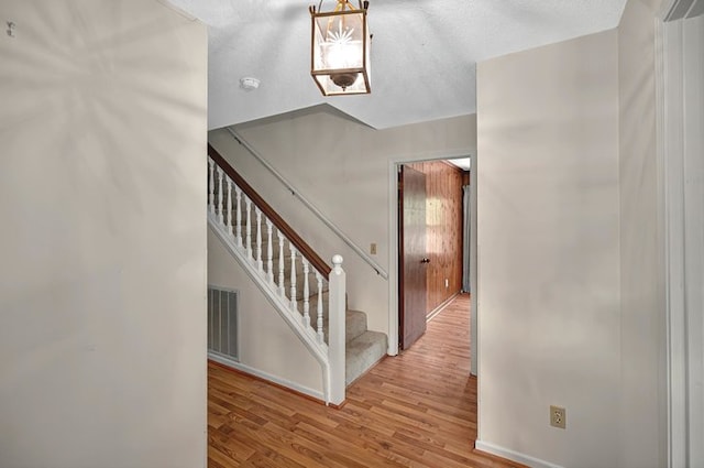 stairway with baseboards, wood finished floors, and visible vents