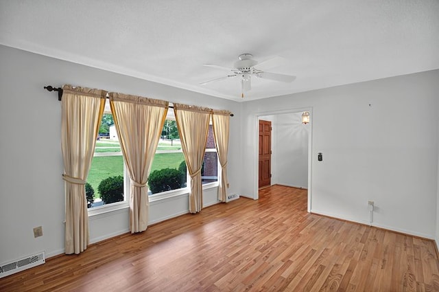 spare room featuring visible vents, a ceiling fan, baseboards, and wood finished floors