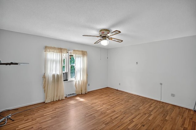 unfurnished room with ceiling fan, a textured ceiling, baseboards, wood finished floors, and visible vents