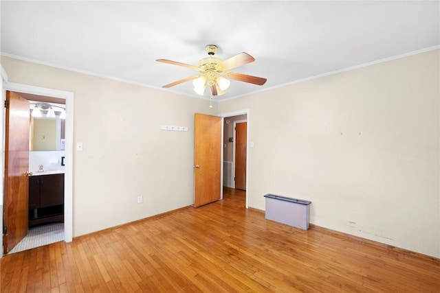 unfurnished bedroom featuring crown molding, connected bathroom, ceiling fan, light wood-style flooring, and baseboards