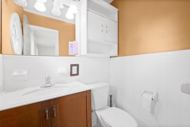 bathroom with vanity, wainscoting, toilet, and tile walls