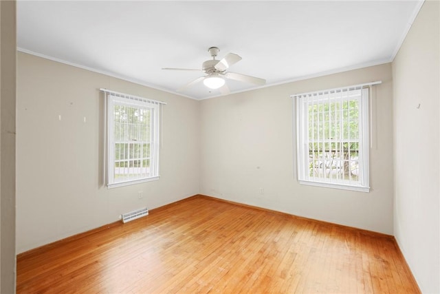 spare room with visible vents, ornamental molding, light wood finished floors, and plenty of natural light