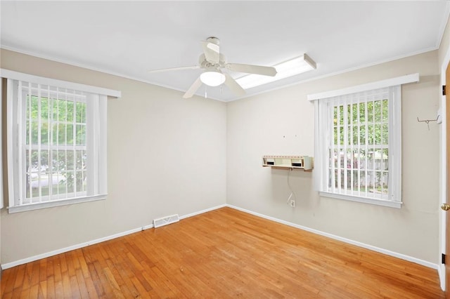 empty room featuring plenty of natural light, baseboards, ornamental molding, and hardwood / wood-style floors