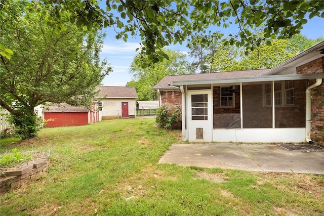 view of yard featuring a storage shed, a patio, an outdoor structure, and a sunroom