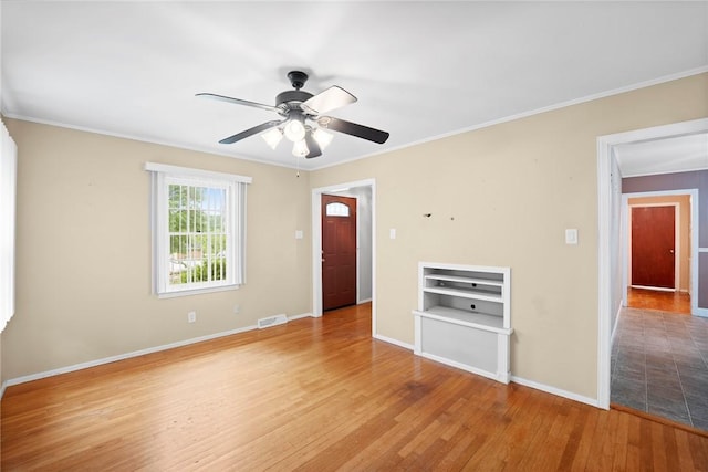 unfurnished room with crown molding, a ceiling fan, baseboards, wood finished floors, and visible vents
