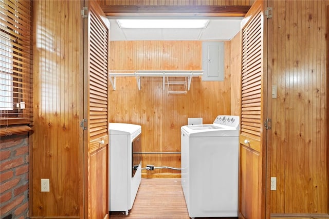 washroom featuring laundry area, wood walls, electric panel, and washing machine and clothes dryer