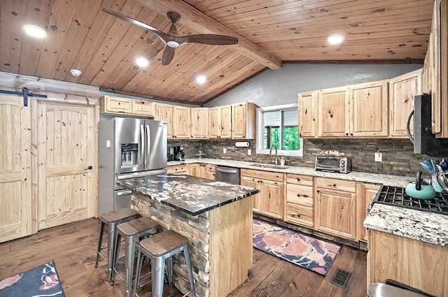 kitchen with light brown cabinetry, appliances with stainless steel finishes, a center island, vaulted ceiling with beams, and tasteful backsplash