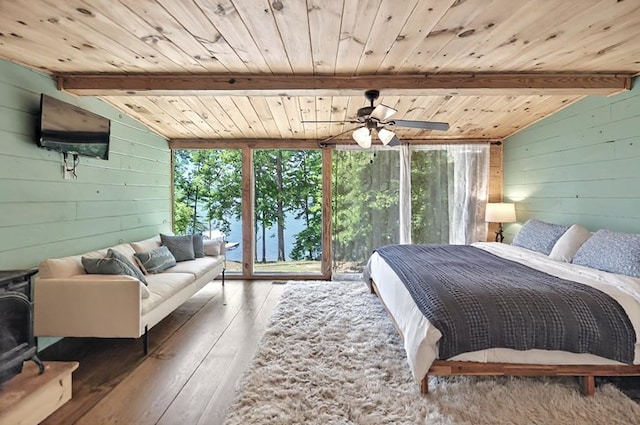 bedroom featuring lofted ceiling with beams, a wood stove, wood walls, hardwood / wood-style floors, and wood ceiling