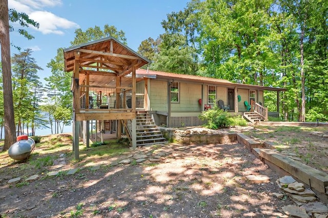 back of house featuring covered porch, stairway, and metal roof