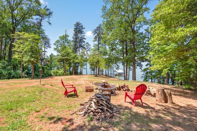 surrounding community with a water view and a fire pit