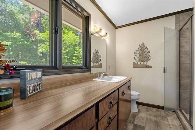 full bath with crown molding, a shower stall, wood finished floors, vanity, and toilet