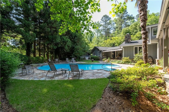 outdoor pool with a lawn and a patio area