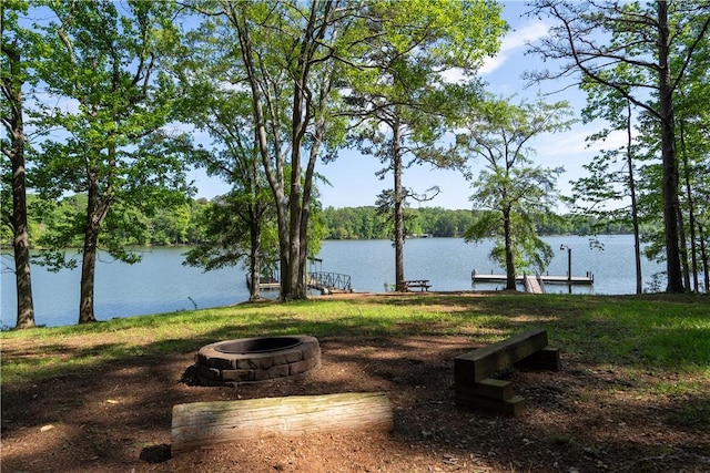 view of home's community featuring a water view, a fire pit, and a dock