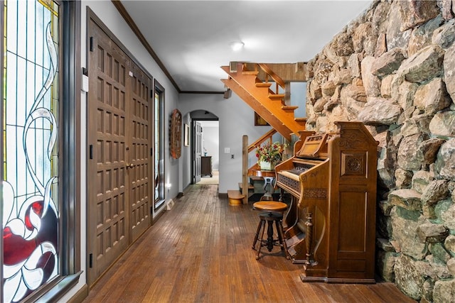 foyer with crown molding, arched walkways, stairs, and hardwood / wood-style floors