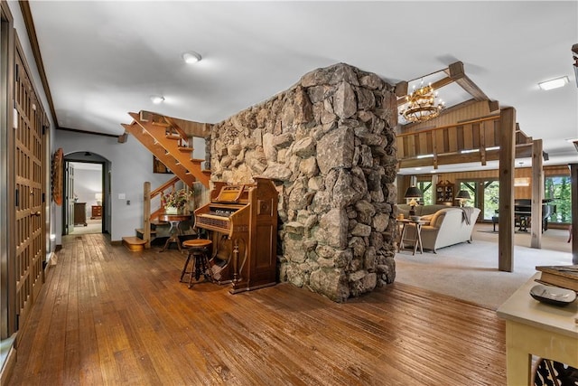 living area with wood-type flooring, arched walkways, a chandelier, and stairs