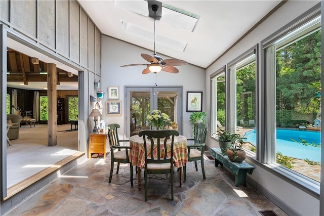 sunroom featuring stone finish flooring, high vaulted ceiling, and a skylight
