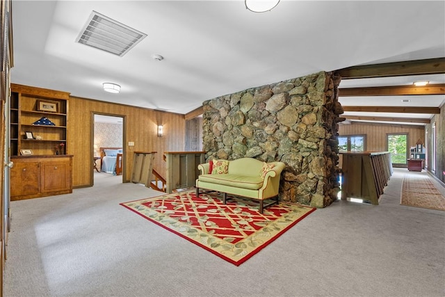 sitting room featuring carpet, wooden walls, and an upstairs landing