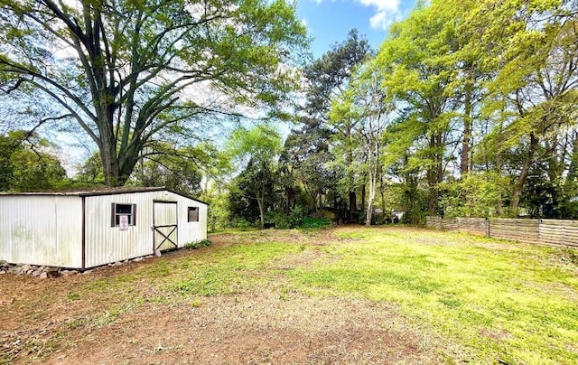 view of yard featuring fence, an outdoor structure, and a storage unit