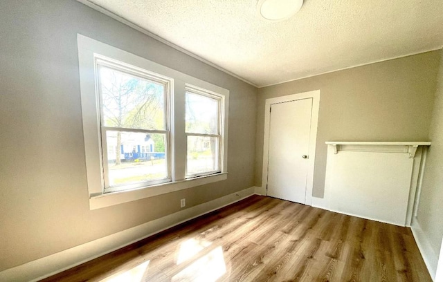 interior space featuring baseboards, a textured ceiling, and wood finished floors