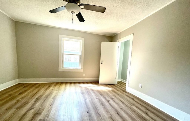 empty room with baseboards, a textured ceiling, ceiling fan, and wood finished floors