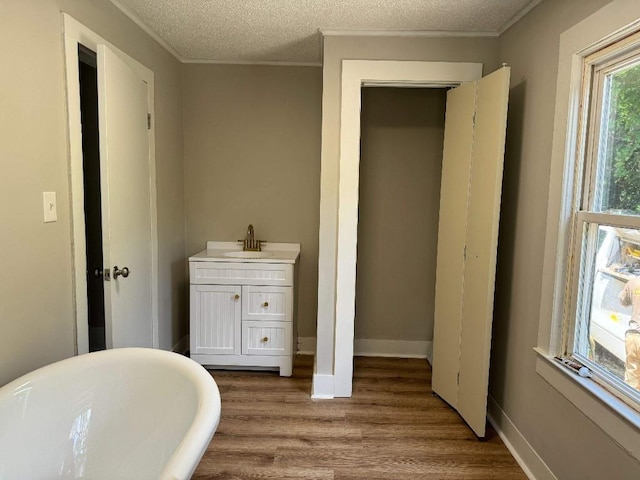 bathroom with crown molding, a freestanding tub, a textured ceiling, and wood finished floors