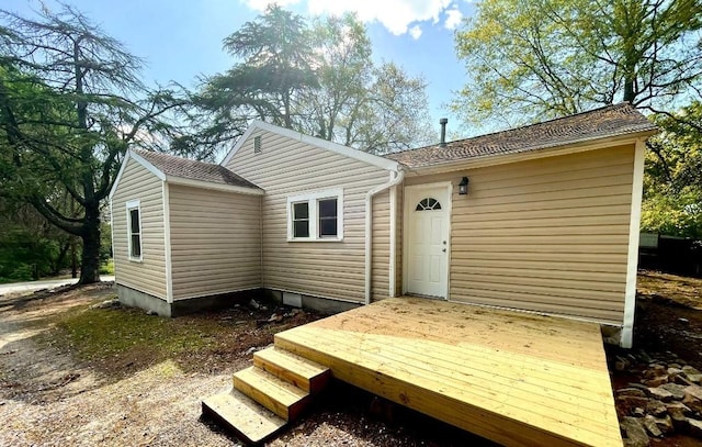 rear view of house featuring a deck and a shingled roof