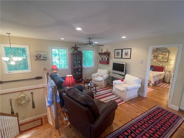 living room featuring recessed lighting, baseboards, ceiling fan with notable chandelier, and light wood-type flooring