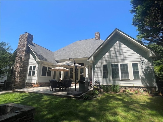 back of house featuring a lawn, a patio area, and a chimney