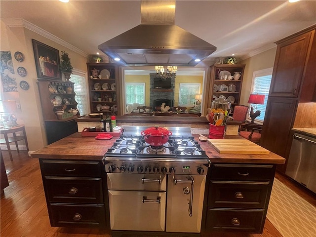 kitchen featuring ornamental molding, wood finished floors, wooden counters, a stone fireplace, and island exhaust hood