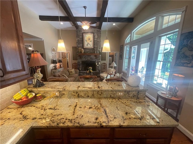 kitchen with baseboards, ceiling fan, light stone counters, and a healthy amount of sunlight