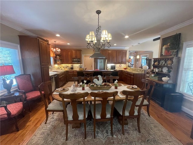 dining room featuring an inviting chandelier, ornamental molding, wood finished floors, and visible vents