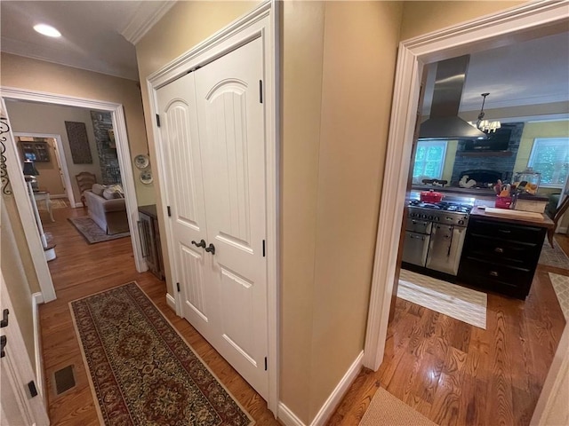 hallway featuring a chandelier, recessed lighting, light wood-type flooring, visible vents, and ornamental molding