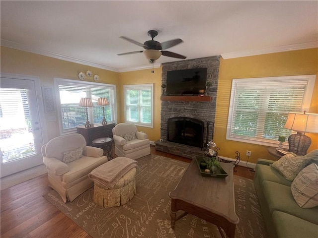 living area with a ceiling fan, a stone fireplace, plenty of natural light, and wood finished floors