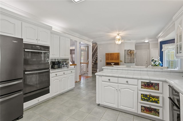 kitchen featuring white cabinets, double oven, tile counters, freestanding refrigerator, and light tile patterned floors