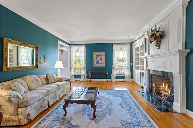 living room with crown molding, baseboards, a fireplace, and wood finished floors