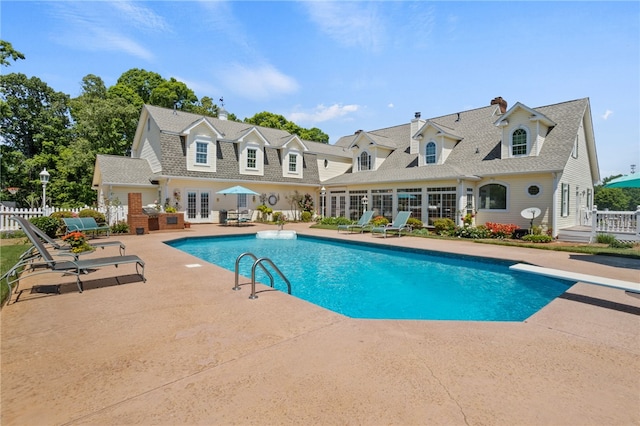 pool featuring a diving board, fence, french doors, and a patio area