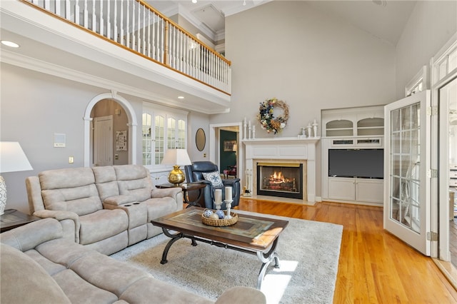 living room featuring a fireplace with flush hearth, crown molding, wood finished floors, high vaulted ceiling, and recessed lighting