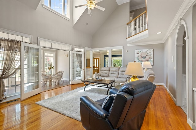 living room featuring a ceiling fan, decorative columns, visible vents, baseboards, and a high ceiling