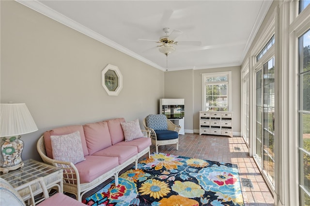 living area with baseboards, ceiling fan, and ornamental molding