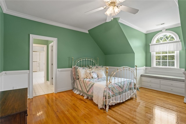 bedroom with crown molding, wainscoting, wood finished floors, and visible vents