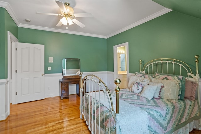 bedroom with crown molding, a ceiling fan, wainscoting, and wood finished floors