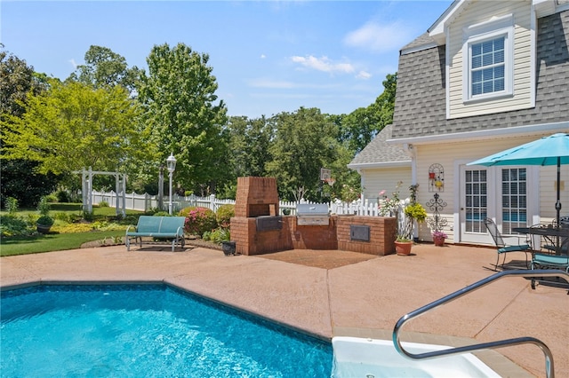 pool featuring fence, a fireplace, a patio, area for grilling, and an outdoor kitchen
