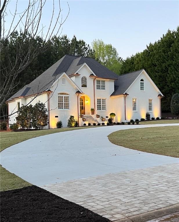 view of front facade with curved driveway and a front yard
