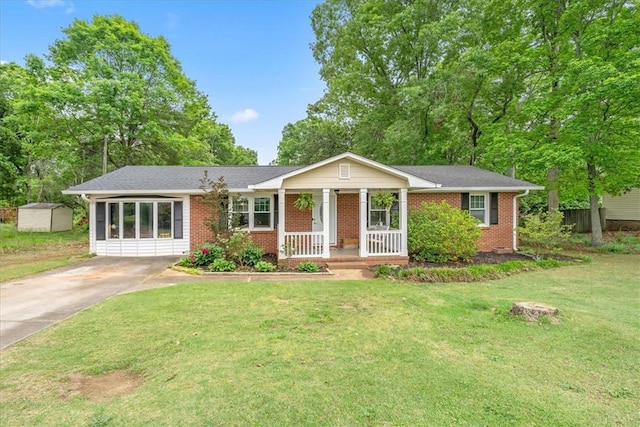 single story home featuring a porch, a front yard, a storage shed, brick siding, and concrete driveway