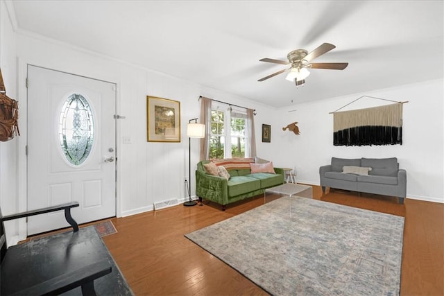 living area with baseboards, a ceiling fan, wood finished floors, and visible vents