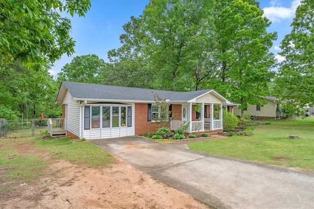 single story home featuring covered porch, a front yard, brick siding, fence, and concrete driveway