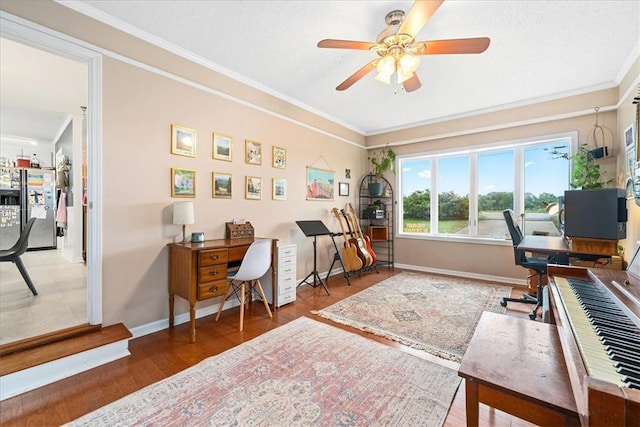 office space featuring baseboards, ornamental molding, a ceiling fan, and wood finished floors