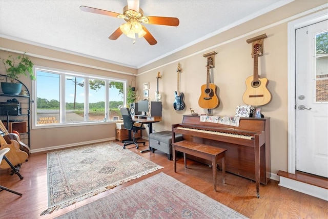 office space with a ceiling fan, ornamental molding, a healthy amount of sunlight, and wood finished floors