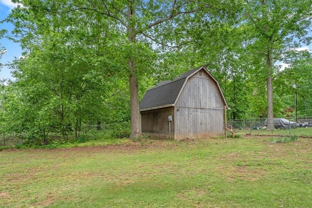 view of barn featuring a lawn and fence