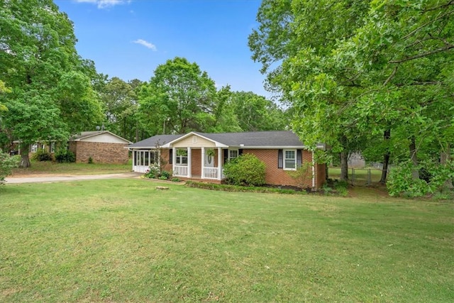 ranch-style house with fence, covered porch, a front lawn, and brick siding
